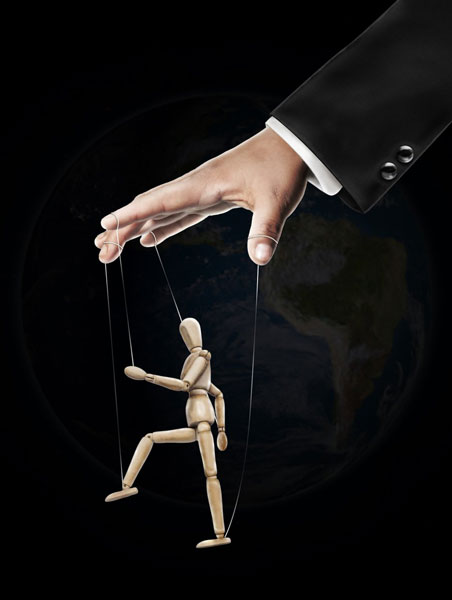 Eine Hand spielt eine Marionette - Sinnbild für Fremdsteuerung